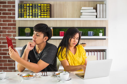 Young Asian Man And Woman Couple Siting At Dinning Table With Laptop And Food Seem Upset And Not Looking At Each Other