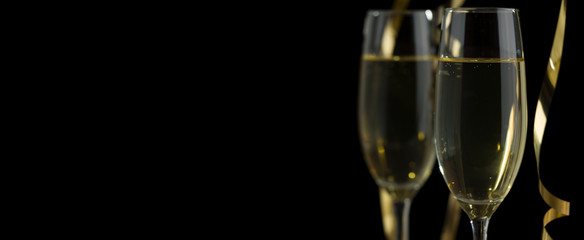Fototapeta na wymiar Two glasses of champagne in front of panoramic black background