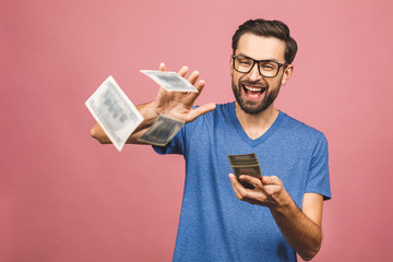 Portrait of a happy young businessman throwing out money banknotes isolated over pink background.