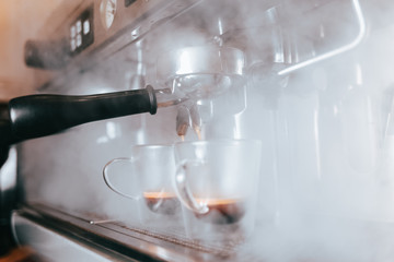 Fragrant espresso flows from a coffee machine into a cup. Making aromatic coffee with professional coffee equipment