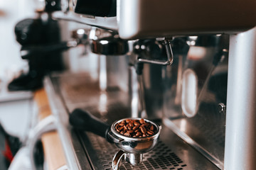 Portafilter with coffee grains lies on a coffee machine