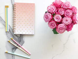 Beautiful notebook with pencils and flowers on marble background - flat lay