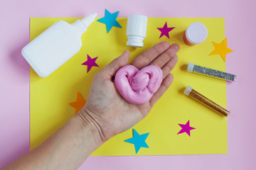 Making slime DIY at home. Girls hand holds homemade pink slime or handgum. Playing with popular...