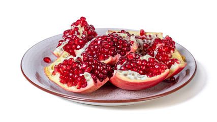 Ripe pomegranate on a plate isolated on white background.