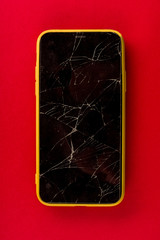 Smartphone with broken screen on red background
