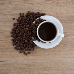 cup of coffee with coffee seeds on wooden table and light brick background