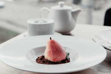 Williams pear shaped mousse glazed dessert on the white plate. Delicious dessert for holiday
