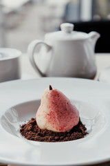 Williams pear shaped mousse glazed dessert on the white plate. Delicious dessert for holiday