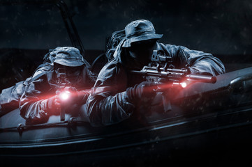 Two fighters of a special unit move at night on the river in a boat. The concept of special...