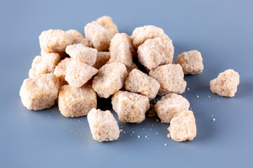 Heap of brown cane sugar on blue background.