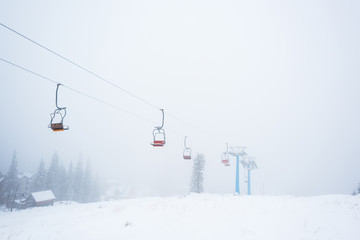 Scenic view of snowy mountain with gondola lift in fog