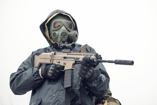 Soldier in gas mask and raincoat with a rifle concept.