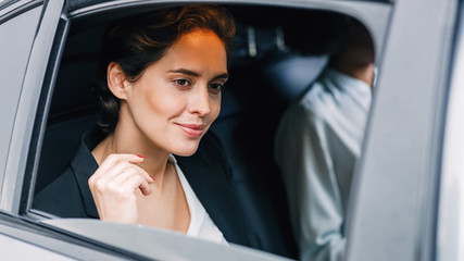 Beautiful businesswoman looking out of the window of a taxi. Young woman traveling by car.