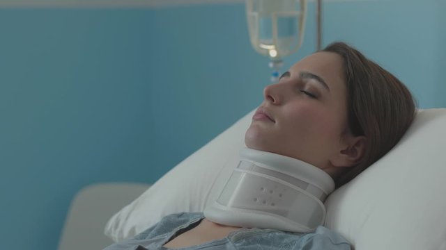 Injured woman lying in a hospital bed with cervical collar and IV