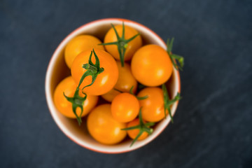 A fresh harvest of home grown yellow miniature tomatoes in ceramic bowls.