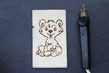 Obraz premium The process of pyrography. Picture with a bear on a board