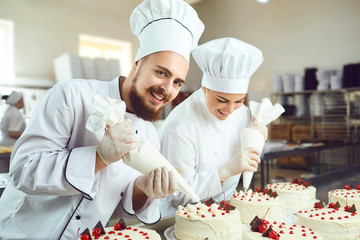 Confectioners with a bag for the cream will decorate the cake.
