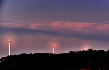 wind turbines at dusk, blades look like wheels.
