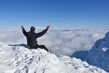 Happy mountaineer raise hand up on top of mountain. Climber enjoy on snowy mountain high above the...
