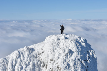 Lonely mountaineer get rest on snowy mountain high above the clouds. Happy climber enjoy in view...