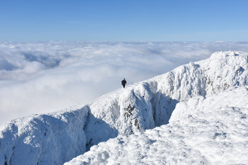 Fototapeta na wymiar Lonely mountaineer get rest on snowy mountain high above the clouds. Happy climber enjoy in view from top of Dry Mountain, Serbia