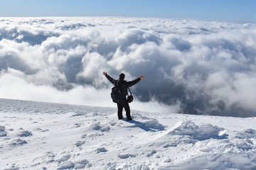 Happy mountaineer raise hand up on top of mountain. Climber enjoy on snowy mountain high above the...