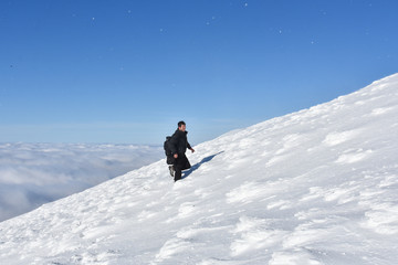 Fototapeta na wymiar Lonely mountaineer get rest on snowy mountain high above the clouds. Happy climber enjoy in view from top of Dry Mountain, Serbia