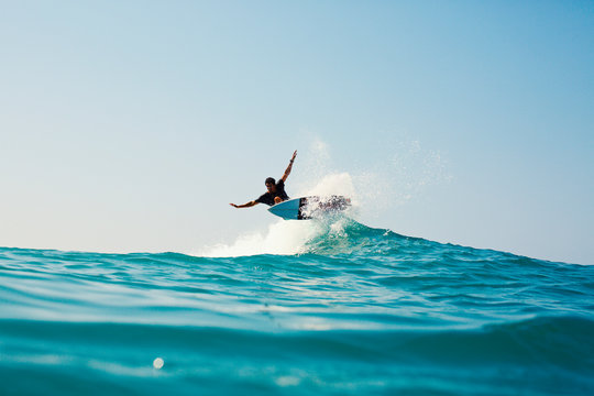 Male surfer riding turquoise blue ocean wave