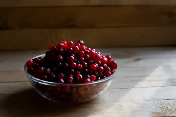 Harvest fresh red cranberries in a glass Cup on a wooden background.
