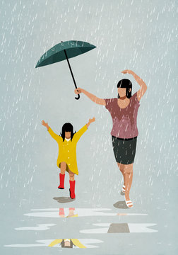 Carefree mother and daughter dancing in rain