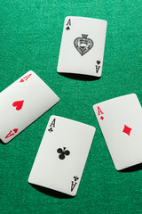 Top view of aces of poker deck on green mat, in vertical