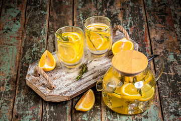 Cold fresh cocktail with lemon. Lemon water with fresh lemons and green plants. lemonade in jar