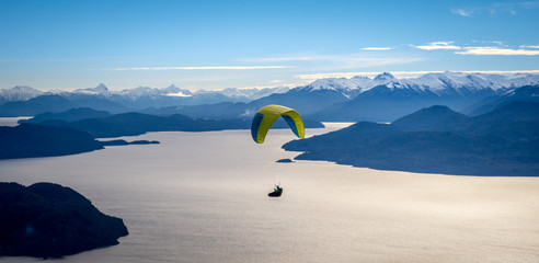 Panoramic view of paragliding over Nahuel Huapi lake and mountains of Bariloche in Argentina, with snowed peaks in the background. Concept of freedom, adventure, flying