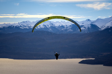 Paragliding over Nahuel Huapi lake and mountains of Bariloche in Argentina, with snowed peaks in the background. Concept of freedom, adventure, flying