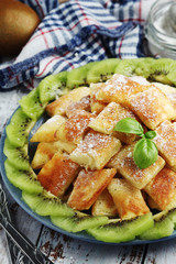 Austrian dessert Kaiserschmarrn served with sugar powder and kiwi fruit