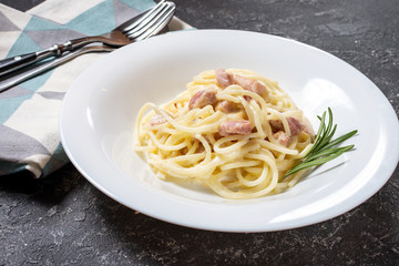 Pasta carbonara served on deep plate decorated with rosemary