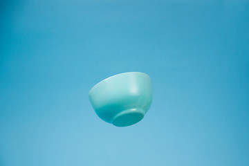 A blue ceramic mattle deep bowl for breakfast flying on blue background.