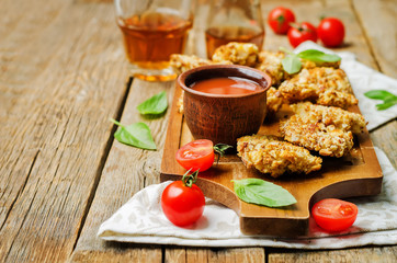 almond crusted chicken tenders with ketchup on a wood background