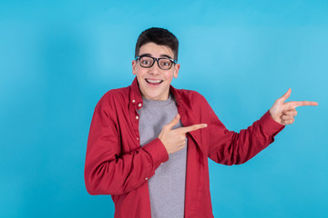 young man or teenage student isolated on color background with surprise pointing or presenting