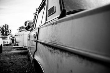 Monochrome side view of an old soviet car parked in a scrapyard.