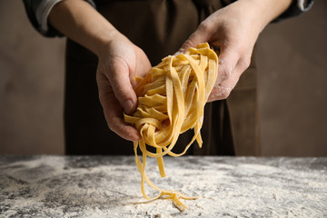 Woman holding pasta at table, closeup view
