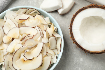 Tasty coconut chips on grey table, flat lay