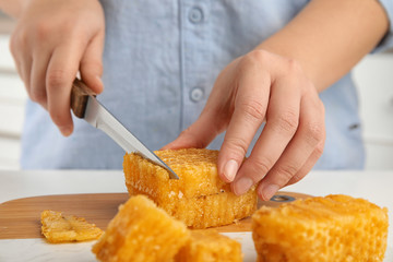 Woman cutting fresh honeycomb at table, closeup