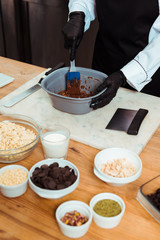 cropped view of chocolatier holding silicone spatula while mixing chocolate in bowl