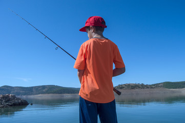 Niño con camiseta naranja pescando 
