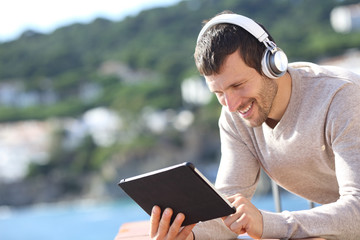 Happy adult man with headphones checking tablet content