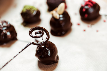close up of swirl near dried raspberries and pistachio powder on fresh made chocolate balls
