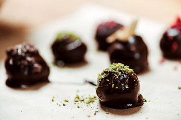 selective focus of sweet chocolate ball with pistachio powder near candies