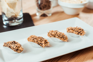 selective focus of prepared chocolate candies with flakes on plate