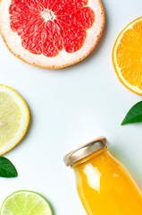 Flat lay composition with glass bottles of juice or fresh, slices of fresh lemon lime orange, green leaves on white background top view copy space. Citrus Juice Concept Vitamin C Fruits